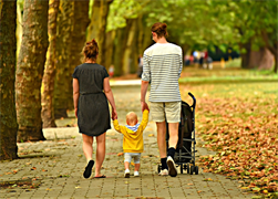 Frau und Mann mit kleinem Kind im Park gehend